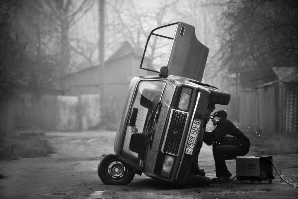 Man repairing the old Soviet car on the outskirts of the city of Mogilev in eastern Belarus by Mihail Kopychko